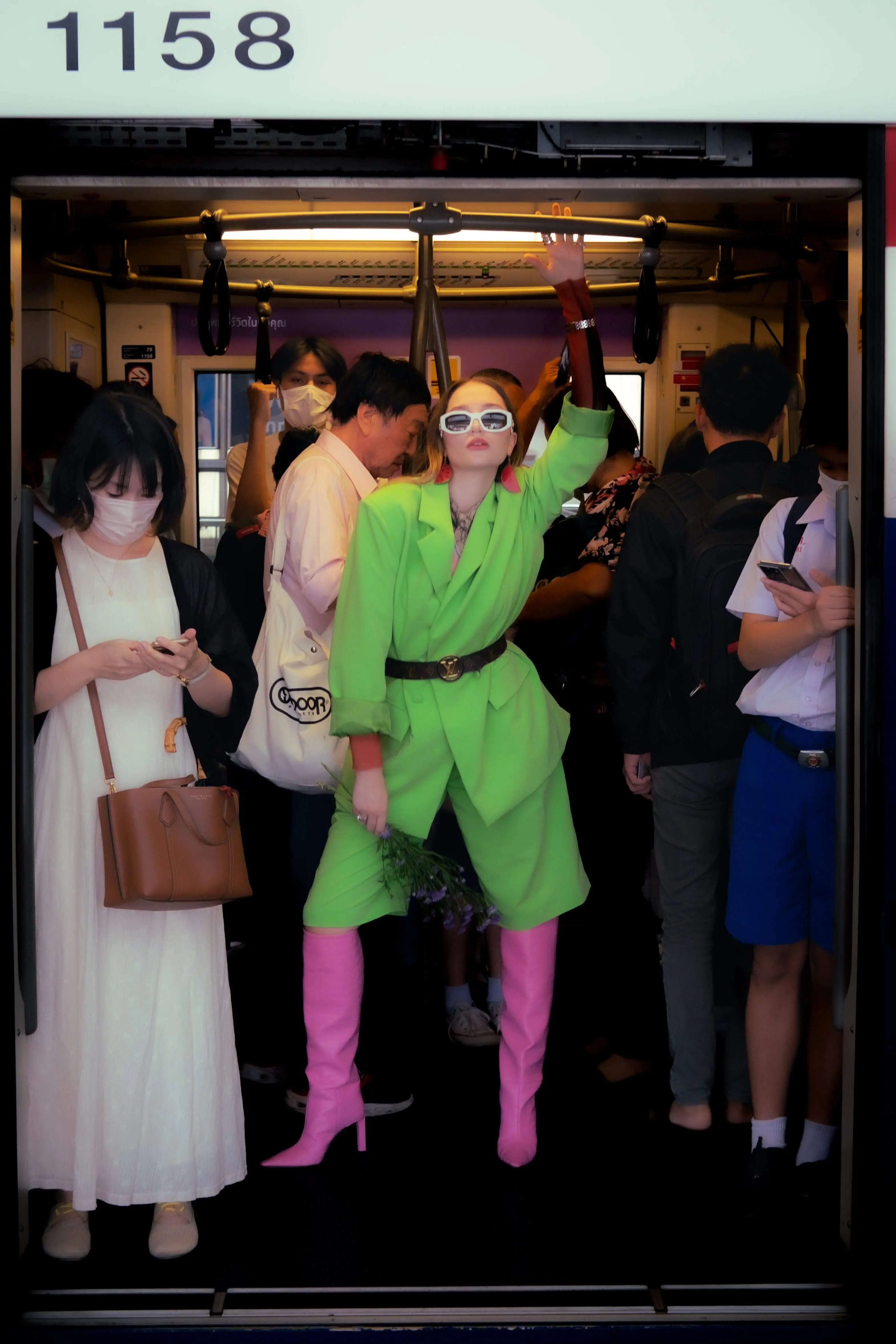 Girl wearing a green suit and pink boots standing in the subway
